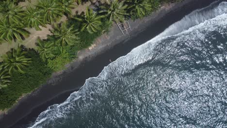 Geheime-Oase:-4K-Drohnenaufnahme-Von-Oben-Nach-Unten-Aus-Der-Luft-Eines-Einsamen-Mädchens,-Das-Am-Unberührten-Schwarzen-Sandstrand-In-Gretek,-Bali,-Liegt