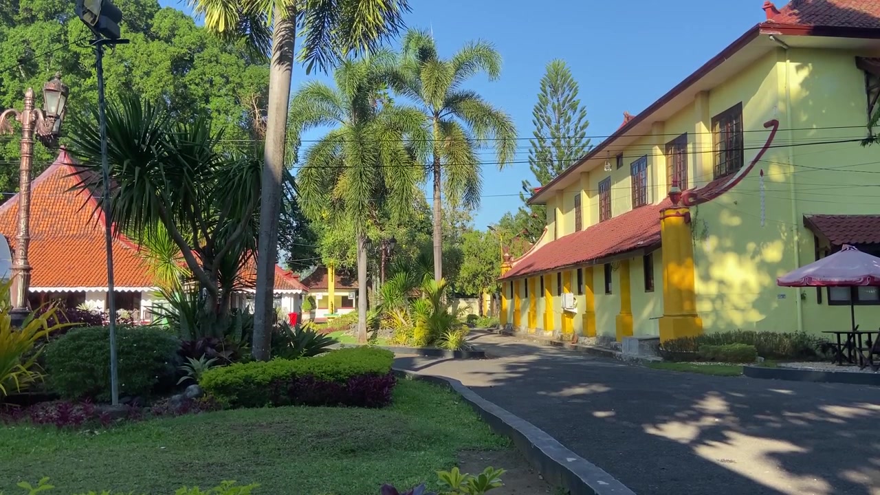 Bangunan Kuning Beratap Merah di Taman Tropis pada Hari yang Cerah