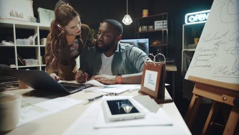 female professional helping african american man worked at laptop in office.