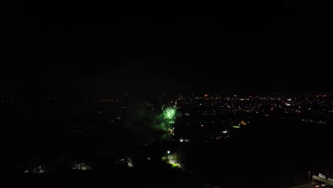 Aerial-shot-of-large-green-fireworks-exploding-in-the-night-sky-at-new-years