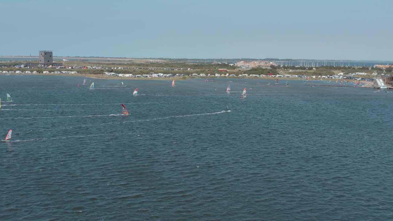 дрон - воздушный снимок многих серферов на синем, волнистом и ветреном море в солнечный день с белыми облаками на острове, зеландия, нидерланды, 30p