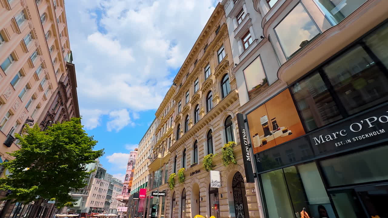 Vienna, Austria - June 9, 2025: Large showcases in the shops of modern brands. Low angle view at the stunning architecture of old town in Vienna, Austria