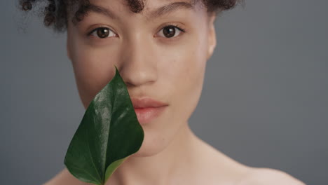 close-up-portrait-beautiful-mixed-race-woman-smiling-caressing-face-with-leaf-touching-smooth-healthy-skin-complexion-enjoying-natural-skincare-beauty-on-grey-background