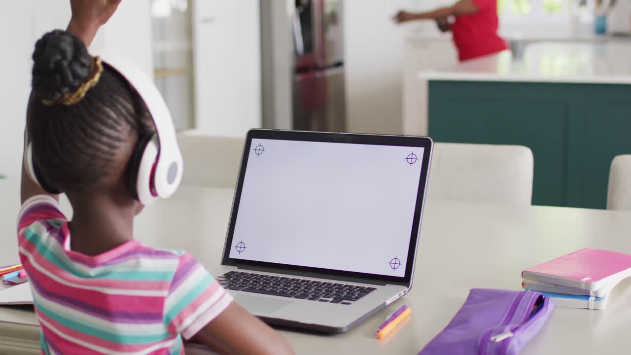 chica afroamericana con auriculares levantando la mano en una lección en línea en una computadora portátil, copia el espacio en la pantalla