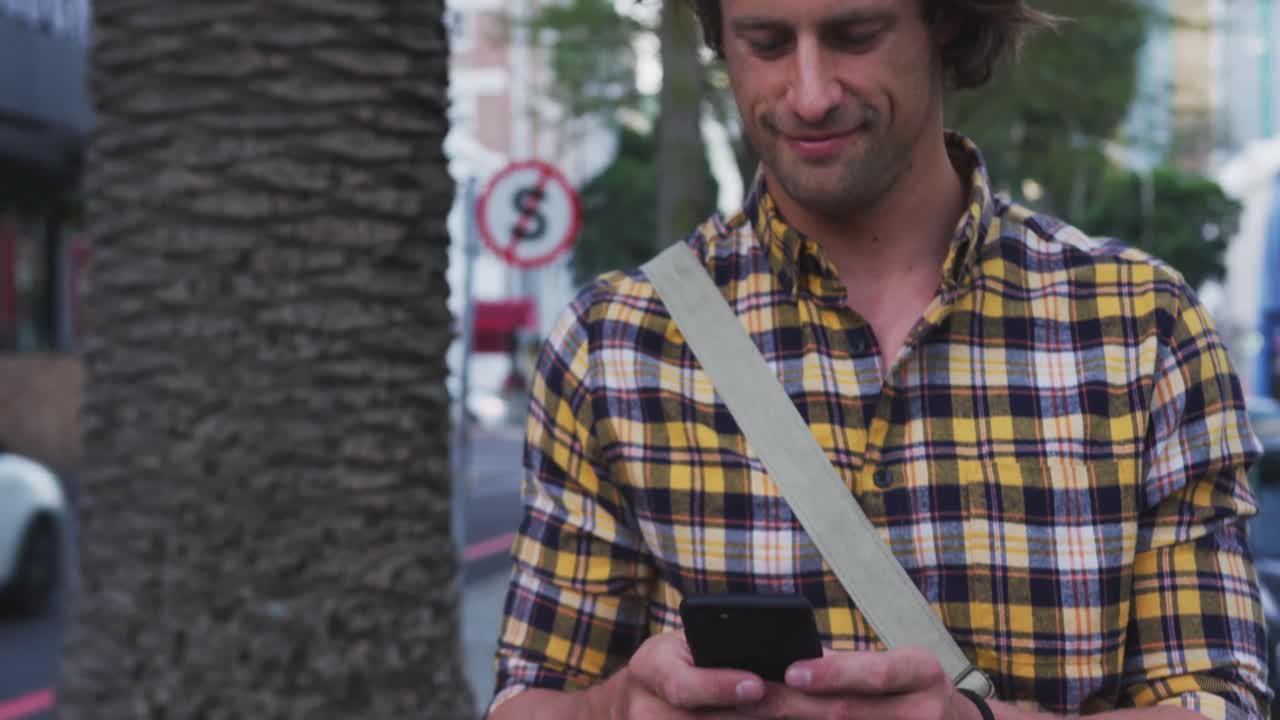 Uomo caucasico sorridente che usa il suo telefono in bicicletta per strada