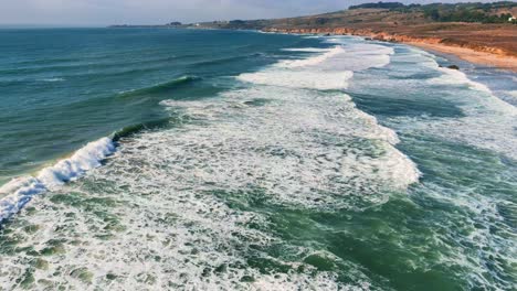 California-Big-Sur-slow-motion-seaside-coast-sandy-beach-along-Highway-One,-famous-road-trip-route-aerial