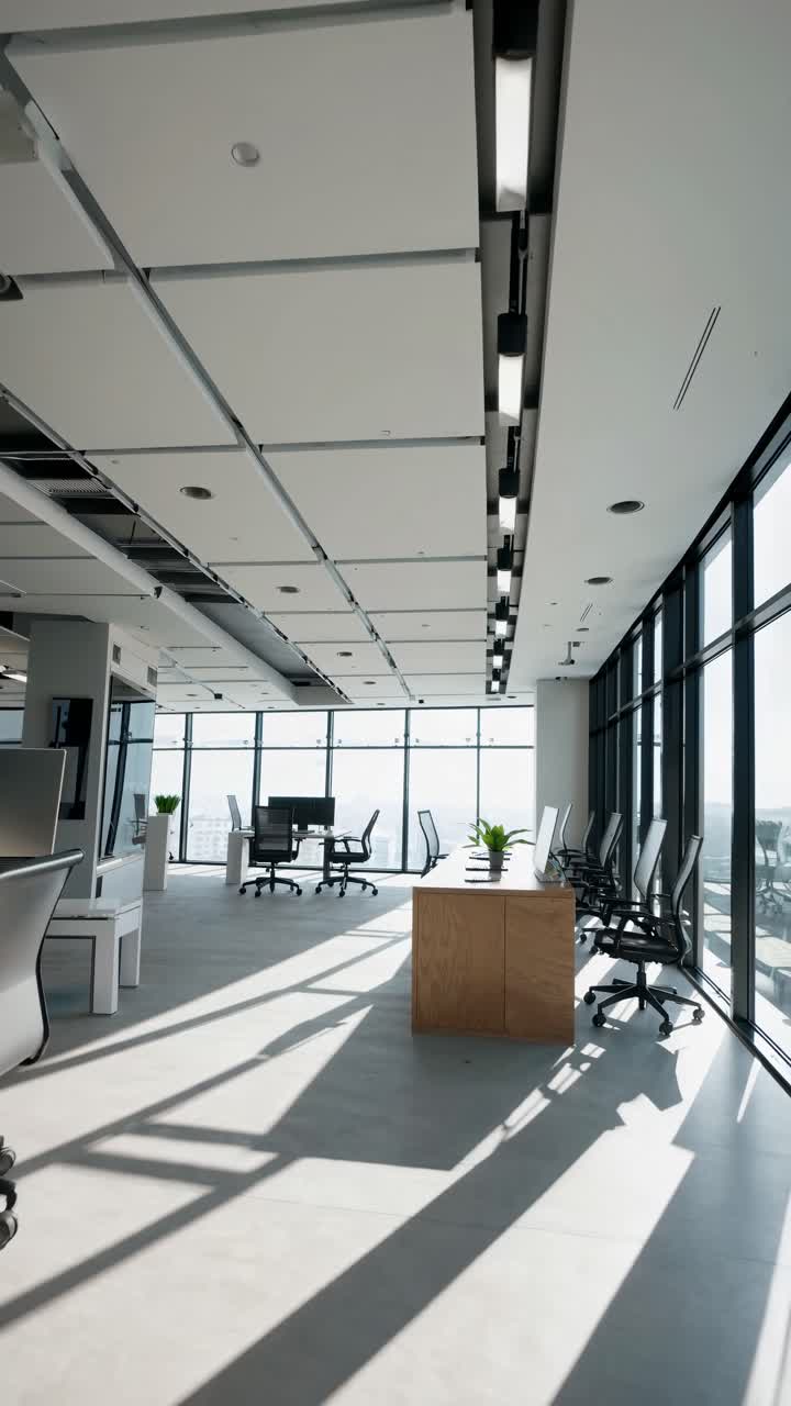 Wide-angle video shot of a modern, minimalist office with floor-to-ceiling windows, sleek furniture