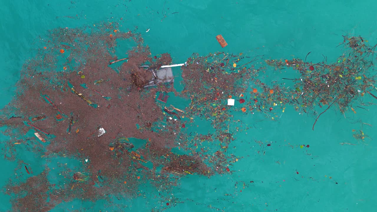 Vista aérea de un parche de basura de plástico rojo y sillas rotas mezclado con fibras naturales en agua azul del océano