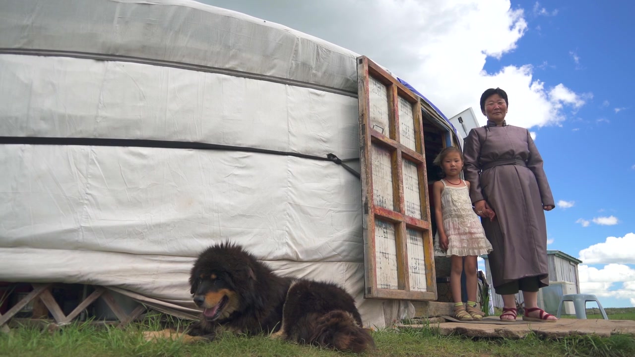 Donna e bambino mongoli in piedi fuori da una yurta tradizionale