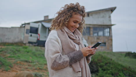 happy tourist watching social media at mobile phone standing camping close up