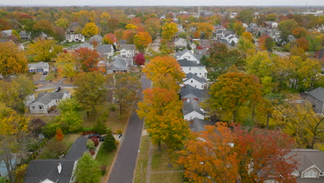 Aerial-trucking-to-the-left-over-beautiful-neighborhood-and-street-with-trees-at-peak-Fall-color-in-Autumn-in-Kirkwood,-Missouri