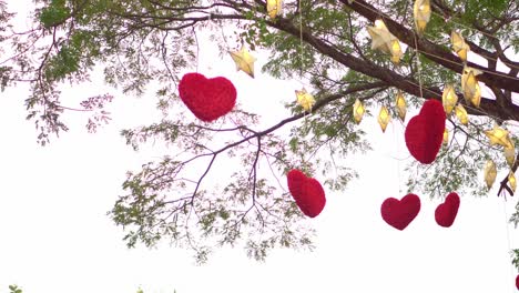 red hearts hanging on a tree with many paper stars and lights twinkling at night. valentine's day concept