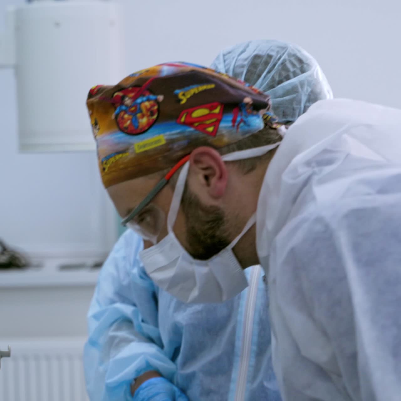 Side view of a nurse in protective uniform and mask. Medical assistant prepares equipment before the operation in the modern operating theater.