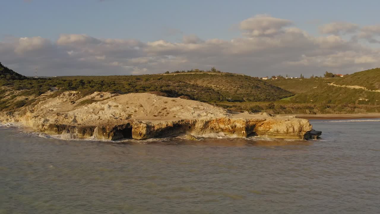 aerial drone shot of waves crashing against rocks along the shoreline