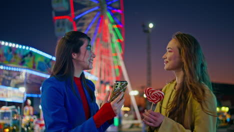 joyful girls take selfie at amusement park. happy best friends make phone photo