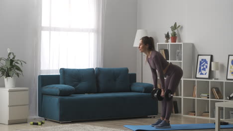 modelo de fitness delgado está entrenando con pesas en las manos de pie en la sala de estar de un apartamento moderno estilo de vida saludable y bienestar entrenamiento de poder de la mujer joven