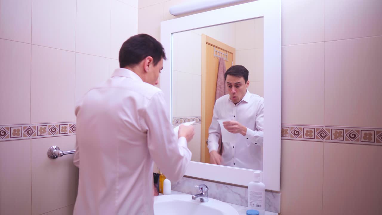 Businessman blowing nose and getting scared in bathroom mirror