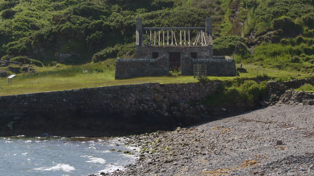 extra wide shot looking at an old derelict crofters cottage at the quay at Tarbet beach,