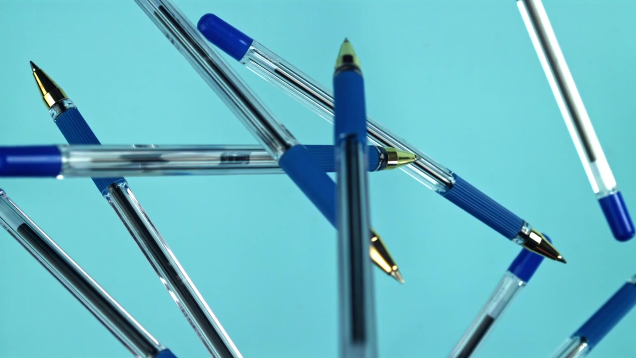 Blue Ballpoint Pens Slowly Rotating on a Light Blue Background