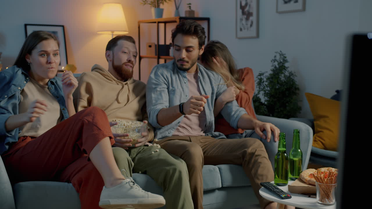 Ystävät katsomassa televisiota ja syömässä