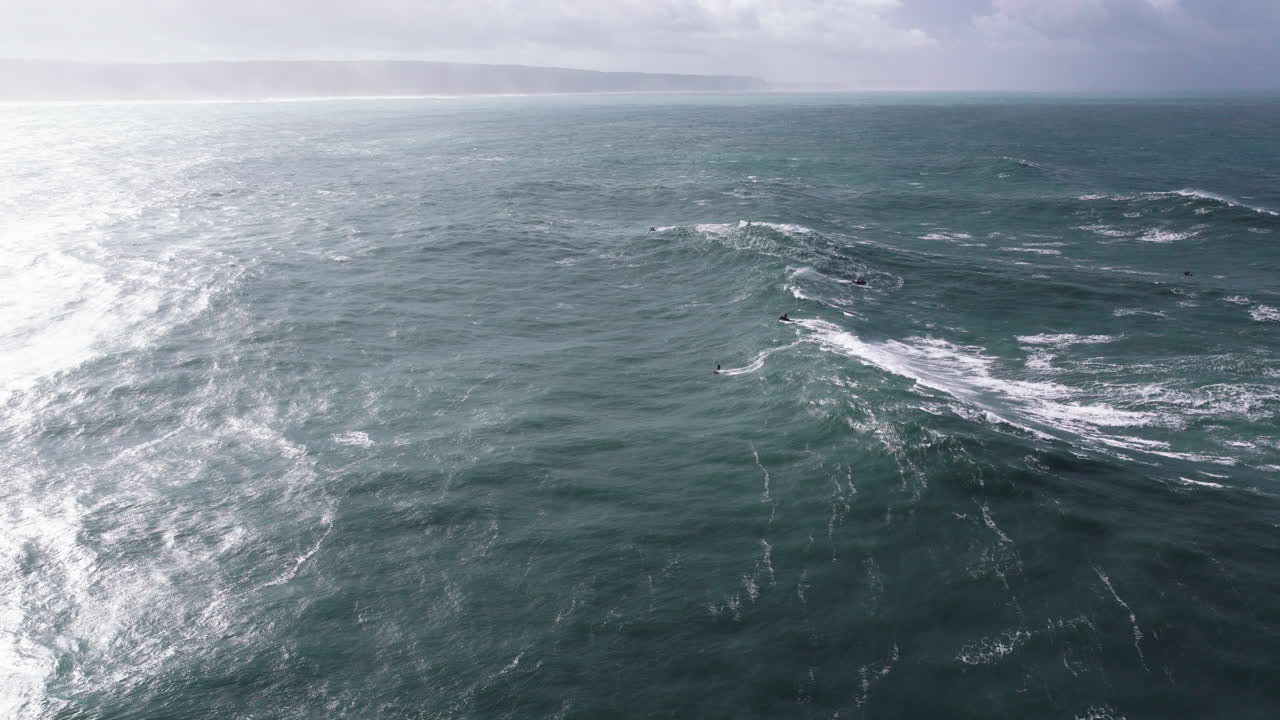 Aerial drone shot of big wave surfer surfing a wave on a day with giant waves in Nazare, Portugal, Europe. Nazaré, big wave surfing town with biggest waves in the world. Professional surfing