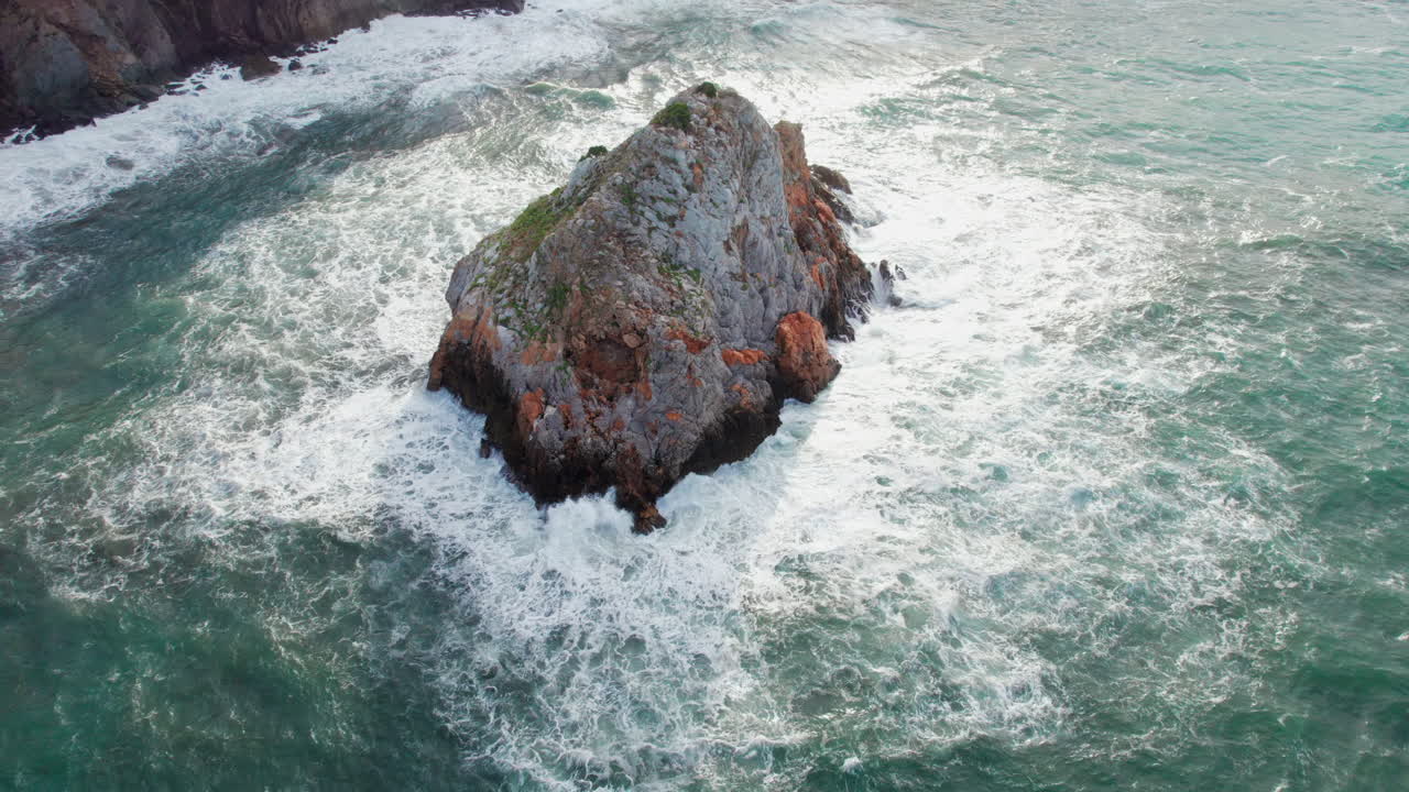 scoglio il morto, cerdeña: vista aérea en órbita sobre el famoso islote y las olas que golpean la roca