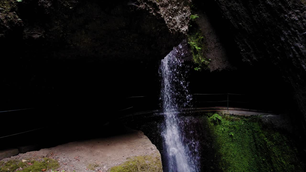 camino de caminata a lo largo de una pequeña cascada aislada con agua que fluye desde un acantilado alto