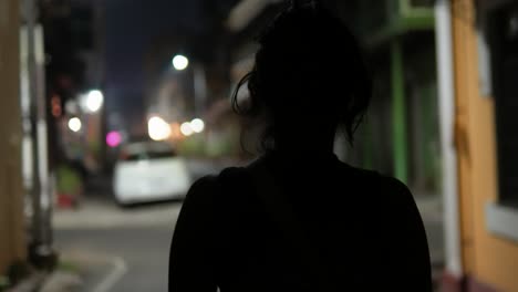 unrecognizable young girl with solitude walking alone on a dimly lit street at night