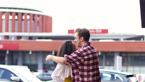 Young-couple-with-suitcase-embracing-near-station