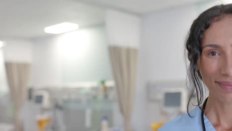 Portrait-of-happy-biracial-female-doctor-looking-at-camera-at-hospital,-copy-space,-in-slow-motion