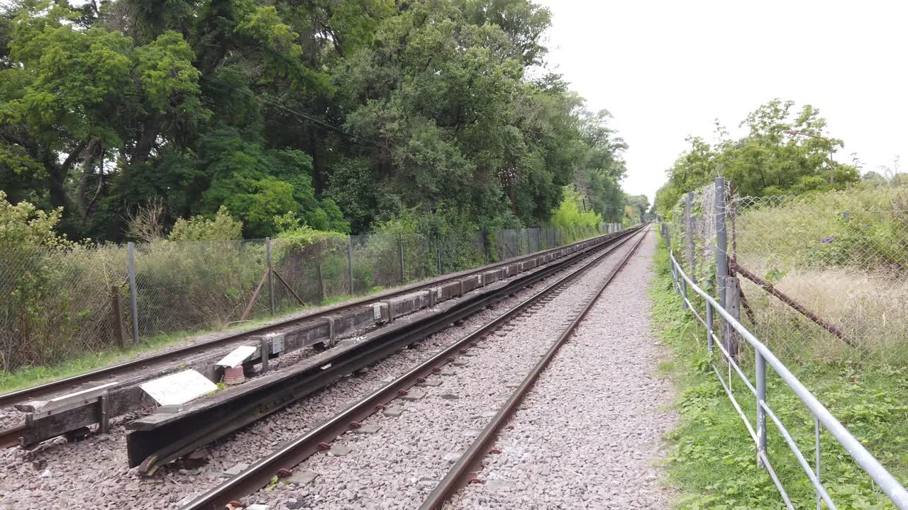 Panning view at empty railway landscape, rails along green forested rural area