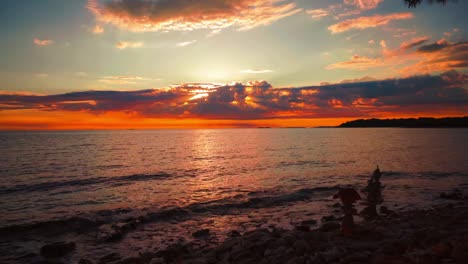 el tiempo de la puesta de sol sobre el horizonte en una pintoresca playa de agua tranquila natural romántica con pequeñas olas en la costa mediterránea croata como una bola grande y naranja. vacaciones de turismo al aire libre puesta de sol cinemagraph bucle de video sin fisuras im 4k uhd.