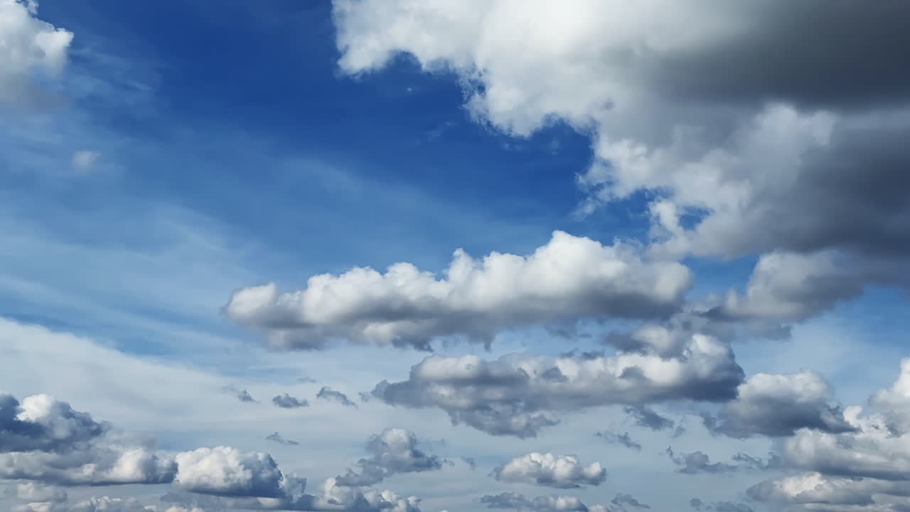 Little fluffy cumulus clouds changing shape in the atmosphere. Low angle view at the clouds floating in the sky. Timelapse.