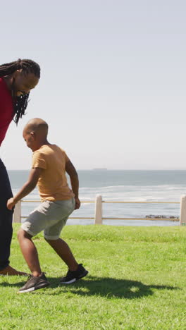 video of happy african american father and son playing soccer outdoors and having fun