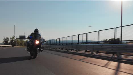 An-unmarked-police-motorcycle-accelerates-on-the-highway-with-emergency-vehicle-lights-on