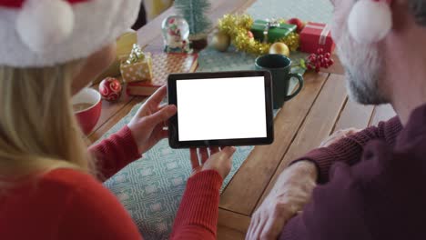 Pareja-Caucásica-Con-Sombreros-De-Santa-Haciendo-Videollamada-Navideña-Con-Tableta,-Copiando-Espacio-En-La-Pantalla