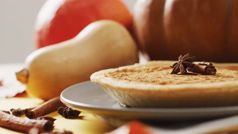 video of autumn leaves, pumpkins, spices and pie on grey background