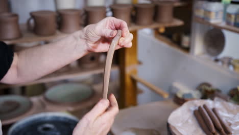 primer plano de un alfarero masculino haciendo manijas de arcilla para tazas en un estudio de cerámica