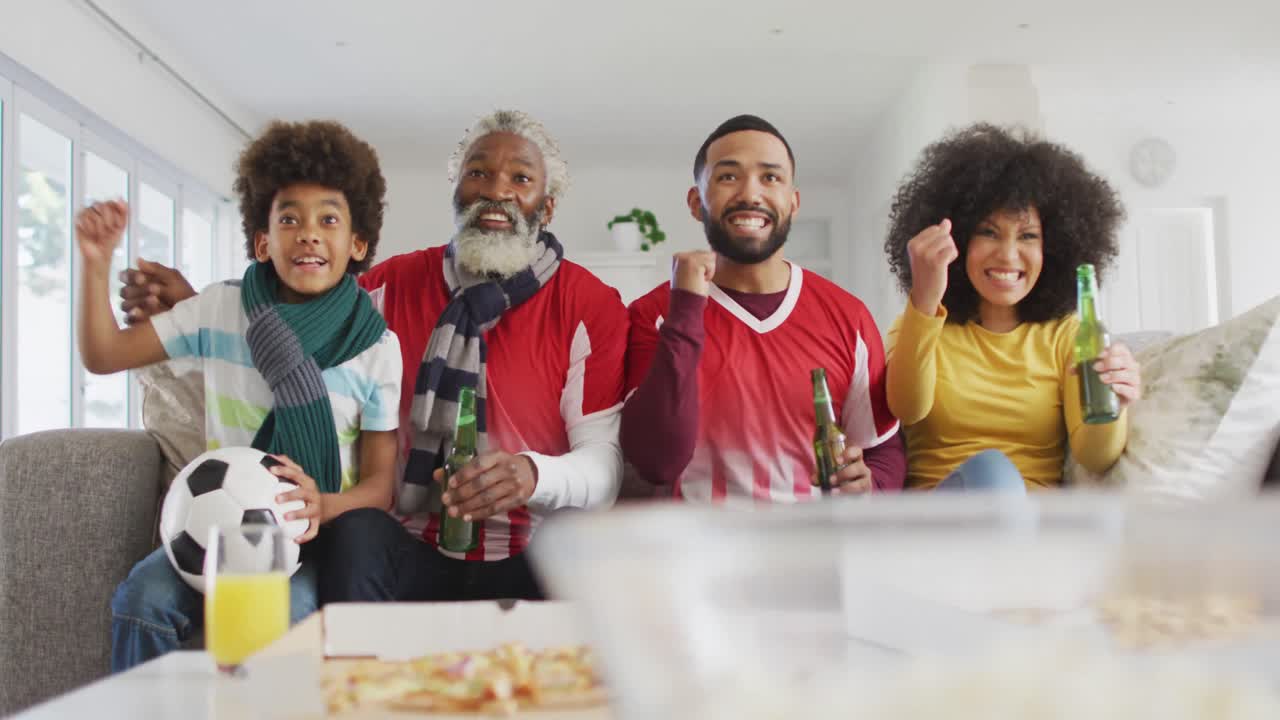 집에서 tv에서 스포츠를 시청하는 동안 다세대 가족이 응원합니다.
