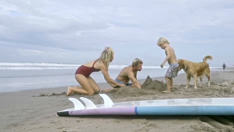 kid building sand castle with parents at ocean beach