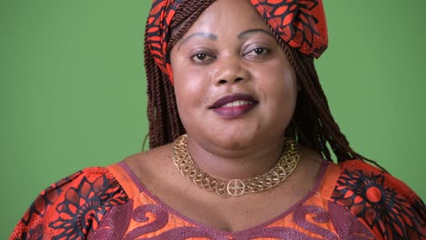 una hermosa mujer africana con sobrepeso que lleva ropa tradicional contra un fondo verde