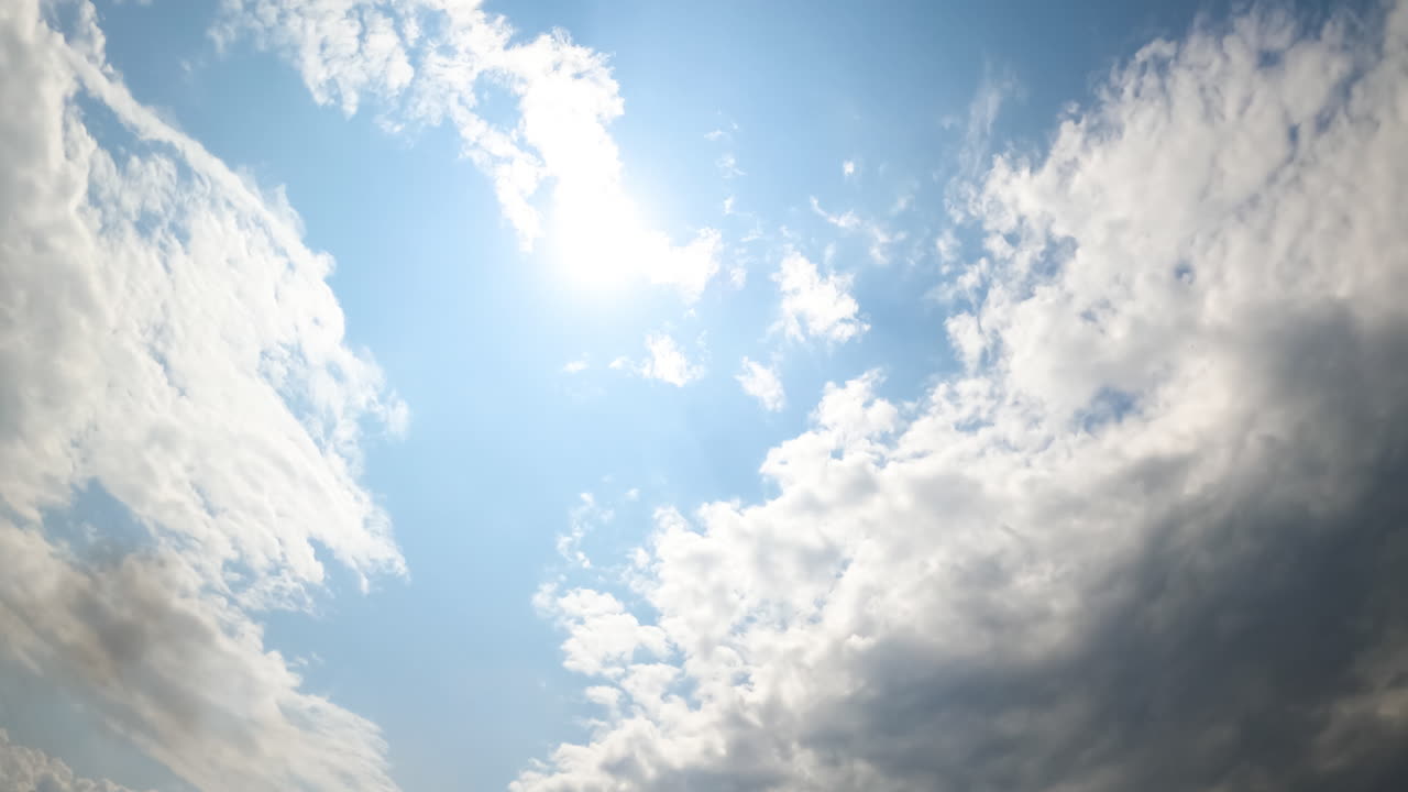 Large rainy clouds covering the sky. Blue sky rarely appears from behind the dramatic cloudscape. Low angle view. Timelapse.