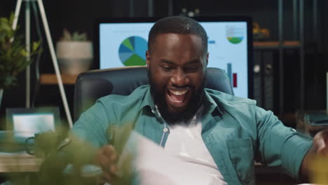 Closeup-happy-african-business-man-celebrating-job-success-in-hipster-office