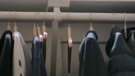 person removing empty hanger from clothing rack inside closet