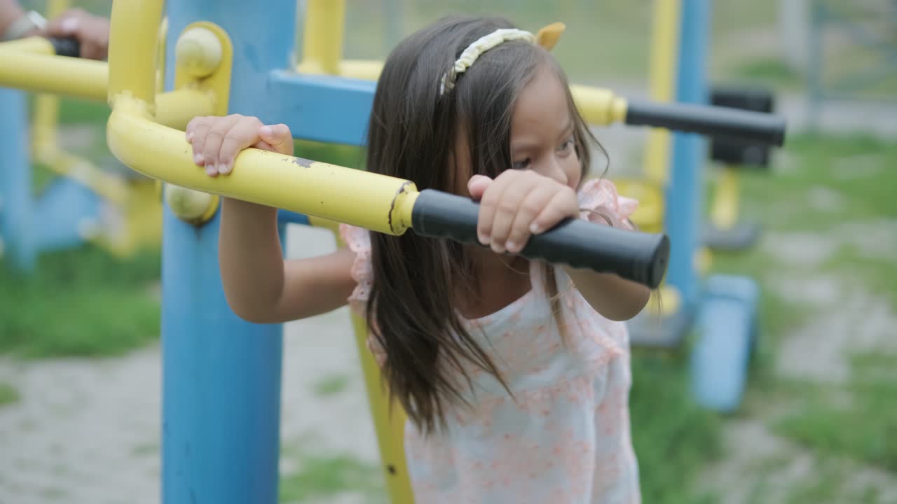 una madre embarazada y su hija joven disfrutan de un tiempo de juego juntos en un patio de recreo en el parque, rodeados de árboles y vegetación