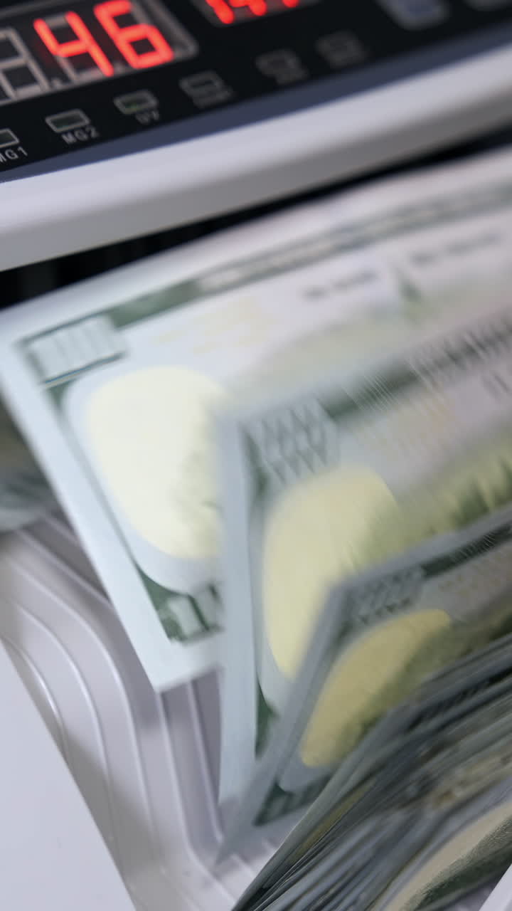 Electronic money counter machine is counting is counting the American hundred-dollar banknotes. The world currency is the US dollar. Vertical video