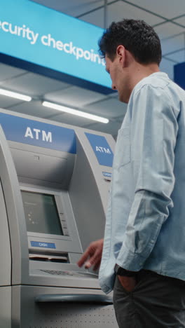 man using an atm at a security checkpoint