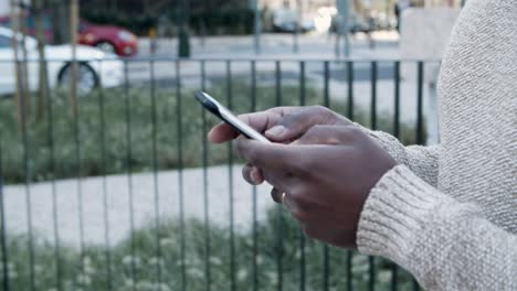 Cropped-view-of-man-texting-on-smartphone-during-stroll