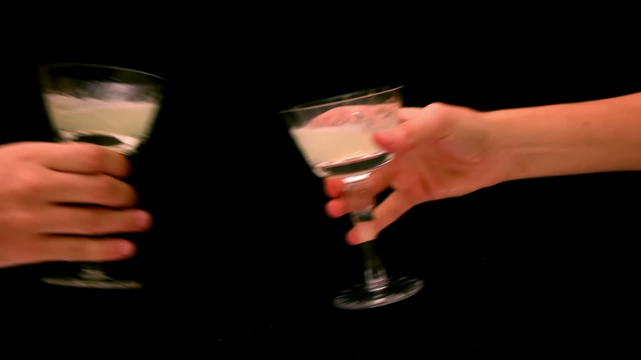 Due mani che fanno tintinnare bicchieri da cocktail in un brindisi