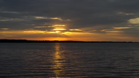 a beautiful reflection of the bright orange sunset over the water surface of lake tisza in abadszalok, hungary.